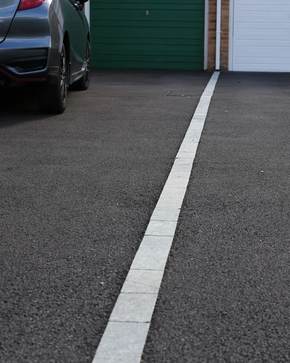 Tarmac driveway with a light kerb edge leading to a garage