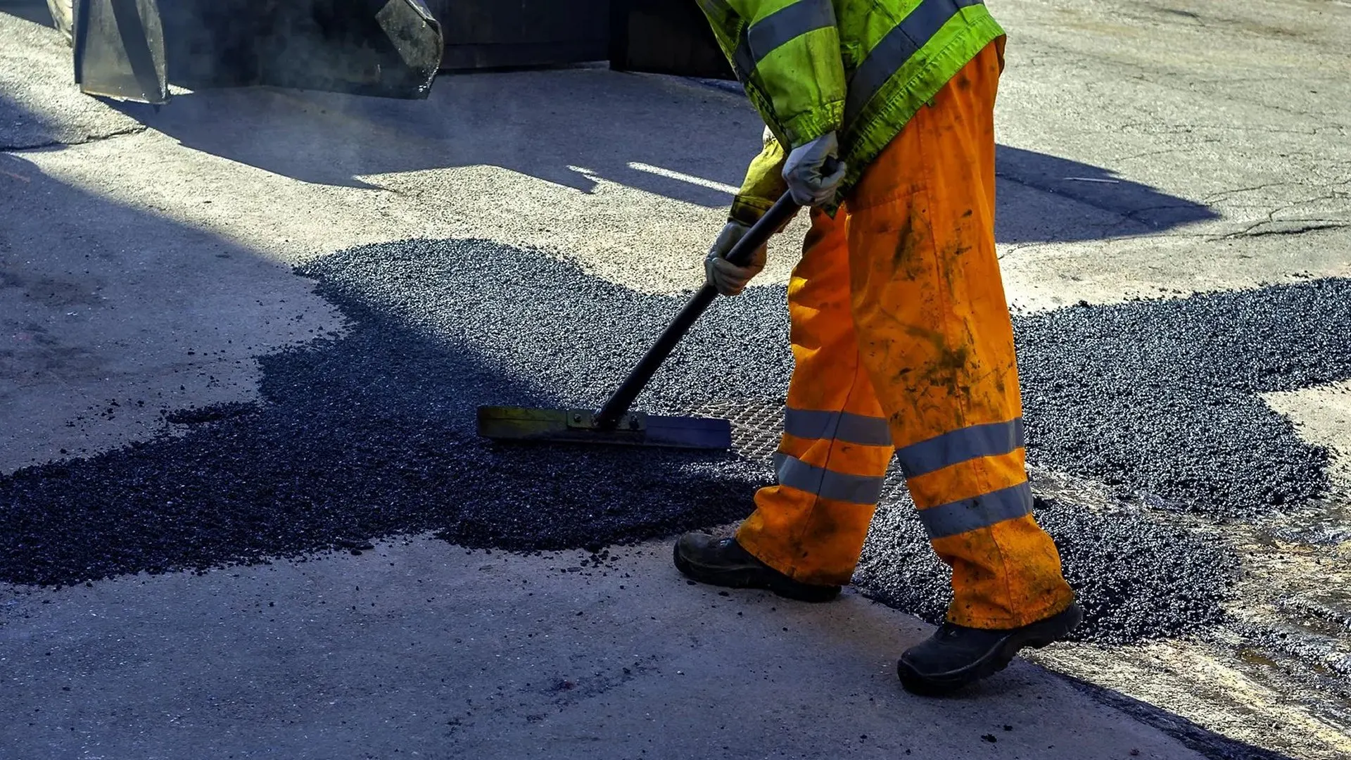 Surfacing operative raking fresh tarmac